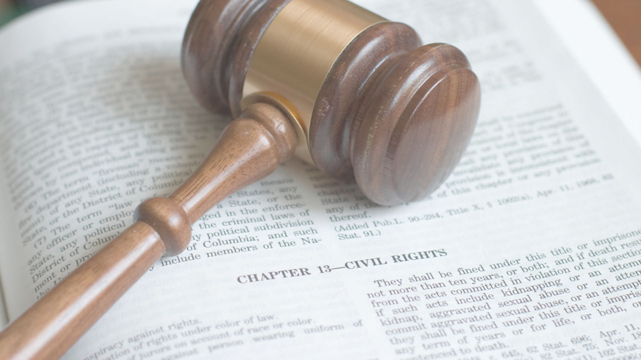 A wooden gavel rests on an open book with the heading "Chapter 13 - Civil Rights." The book's text is slightly out of focus, emphasizing the gavel's role in law and justice.